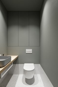 a white toilet sitting in a bathroom next to a sink and counter top under a mirror