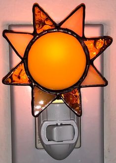 a light that is on the side of a wall with an orange glass sun design