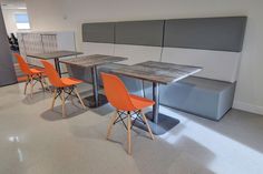 three orange chairs are sitting at a table in an office with gray and white walls