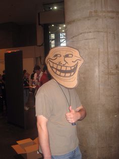 a man wearing a creepy mask and listening to headphones while standing next to a pillar