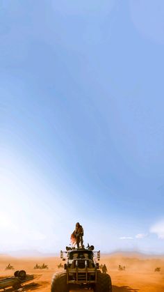 a person riding on top of a vehicle in the desert