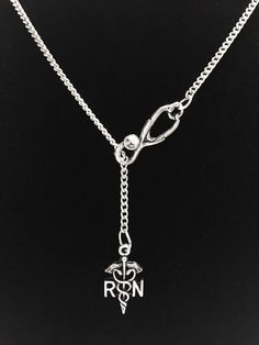 a silver necklace with a medical symbol hanging from it's center link on a black background