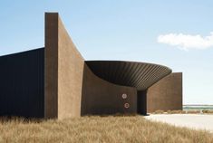 the building is made out of concrete and has a curved entrance that leads into an open field