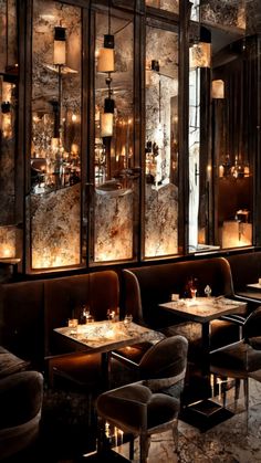 a dimly lit dining room with marble walls and floor to ceiling windows, lighted by candles