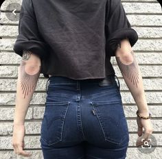 the back of a woman's jeans with tattoos on her arms