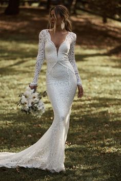 a woman in a wedding dress walking through the grass