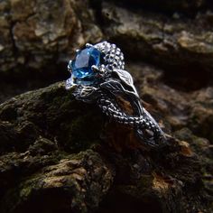 a close up view of a ring on some rocks, with the blue stone in the middle