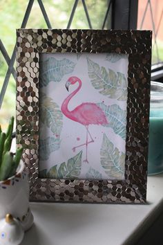 a pink flamingo standing in front of a window next to a potted plant