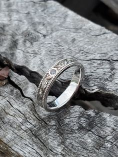 the wedding ring is sitting on top of a piece of driftwood, with an intricate design