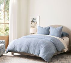 a bed with blue comforters and pillows in a bedroom