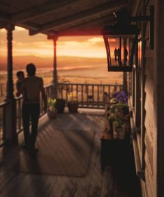 two people are walking down the porch towards the ocean at sunset or sunrise, while the sun is setting