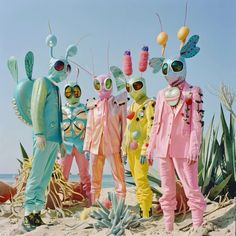 four people in colorful costumes standing on the beach with cactuses and succulents