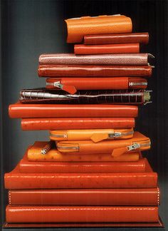 a stack of orange suitcases sitting on top of each other in front of a black wall