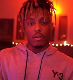 a young man with dreadlocks standing in front of a red light and looking at the camera