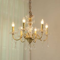 a chandelier hanging from the ceiling in a room with white walls and curtains