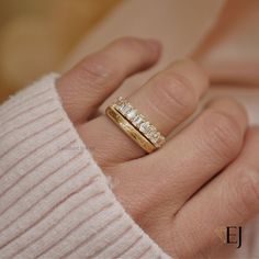 a woman's hand with a gold wedding band and two diamond rings on it