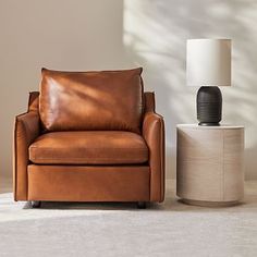 a brown leather chair next to a white lamp