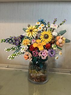 a vase filled with lots of colorful flowers on top of a table next to a wall