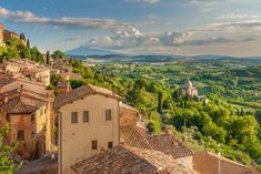 an aerial view of some buildings and trees in the distance with mountains in the background