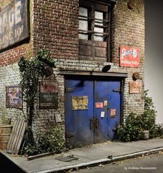 an old brick building with blue doors and vines growing on the outside, next to a sidewalk