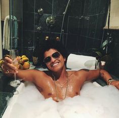 a shirtless man in a bubble bath holding a wine glass and posing for the camera