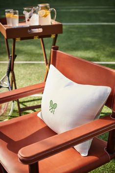 a chair with a pillow on it and a tennis racket in the back ground