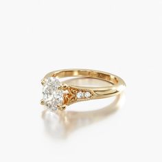 a yellow gold engagement ring with an oval cut diamond in the center and side stones