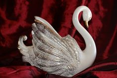 a white swan figurine sitting on top of a red velvet covered table cloth