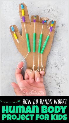 a person holding up a hand made out of paper with green and yellow pens on it