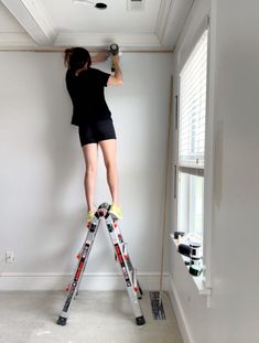 a woman on a ladder painting the ceiling