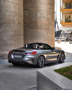 the bmw z4 roadster convertible is parked in front of a large concrete pillar