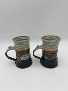 two black and white coffee mugs sitting next to each other