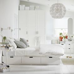 a white bedroom with lots of furniture and accessories on the floor, including a bed