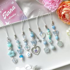 a bunch of necklaces sitting on top of a white tray next to flowers and a card