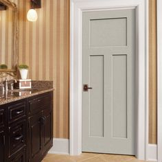 a white door in a bathroom next to a vanity and mirror with lights on it