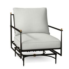 an upholstered chair with white fabric and brass accents