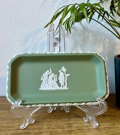 a green tray sitting on top of a wooden table next to a potted plant