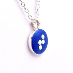 Choose any 1 letter in braille on this small round pendant. The necklace is made out of polymer clay in a silver-tone pendant cup with your choice of clay color. It comes with a choice of silver plated chain or leather cord (18-20 inches) and white or black metal dots. The pendant is sealed with a coat of glaze. The flower measures 1 inches tall (25mm) including bail/loop 3/4 inch across (19 mm) This example is made of dark ultramarine clay but can be made in any color you choose (see photos for Braille Necklace, 16 Necklace, Clay Color, Silver Chain For Men, Peacock Green, Lace Edging, Silver Chain Necklace, Round Pendant, Personalized Necklace