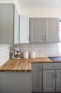 a kitchen with gray cabinets and wooden counter tops