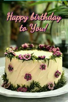 a white cake with pink flowers on it and the words happy birthday to you written below