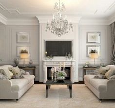 a living room filled with furniture and a chandelier hanging from the ceiling over a fire place