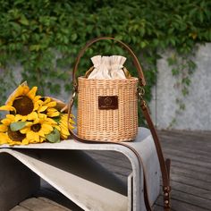 a sunflower sitting on top of a bench next to a wicker bag