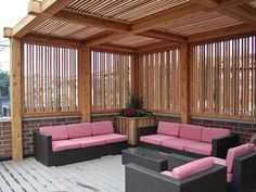 an outdoor living area with wicker furniture and pink cushions