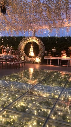 an indoor wedding reception with lights on the floor and greenery in the center, surrounded by candles