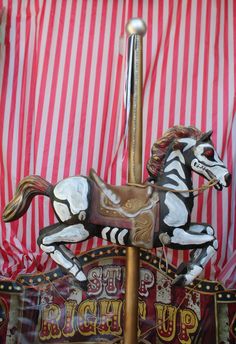 a merry go round horse on display in front of a red and white striped curtain