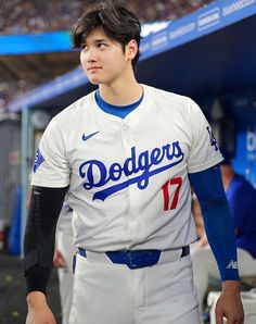 a dodgers baseball player is standing in the dugout with his hand on his hip