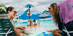 two women sitting in lawn chairs talking to each other at the pool with towels hanging over their heads