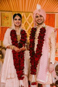 two people standing next to each other in front of flowers