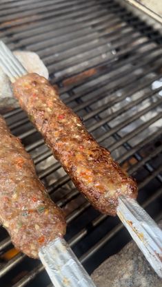 two sausages are being cooked on the grill