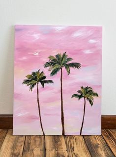 three palm trees against a pink sky painted on an acrylic canvas with wood flooring